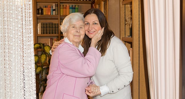Pflegekraft von Iwona Szwedyc wird von Seniorin lächelnd umarmt