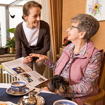Pflegekraft von Iwona Szwedyc liest mit einer Seniorin ein Magazin